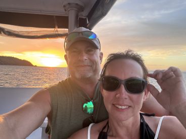 A couple enjoys a romantic sunset selfie on a boat, capturing the perfect moment of their scenic cruise.