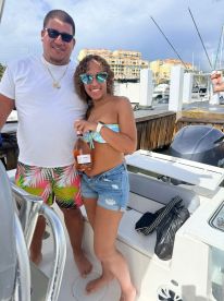 A cheerful couple poses on a boat, holding a bottle of rosé, perfect for celebrating special moments on the water.