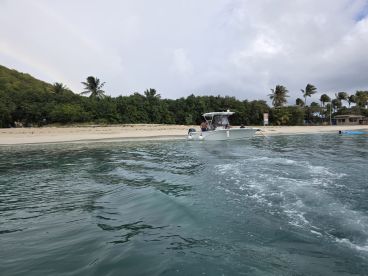 A boat approaches a serene beach, with guests enjoying the scenic view — a perfect setting for water activities and relaxation.