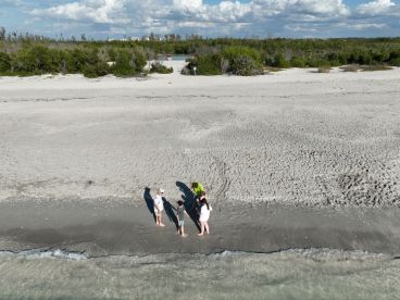 A group of people enjoys a beach day, exploring the shoreline and creating memories at a picturesque sandbar. Perfect for family outings and fun in the sun.