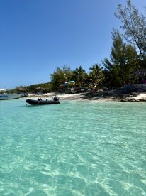 A serene view of a boat docked near a beautiful beach with crystal-clear turquoise waters, perfect for a relaxing day by the shore.