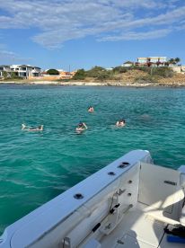 A group enjoys snorkeling in the clear turquoise waters, creating a perfect backdrop for a fun day on the water.