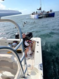 A father and son enjoy a moment on their boat while others swim nearby, creating a memorable family experience on the water.