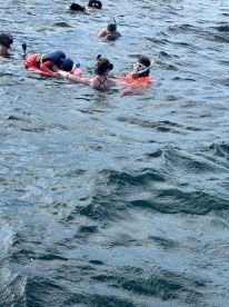 A family enjoys a snorkeling adventure in clear waters, with children and adults actively engaging in the fun — perfect for memorable aquatic experiences.