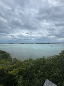 A stunning view of a tranquil coastline with turquoise waters and overcast skies, perfect for showcasing the beauty of island destinations.