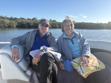 A cheerful couple enjoys a relaxing moment on a boat, surrounded by serene waters and lush greenery — perfect for a peaceful day on the water.