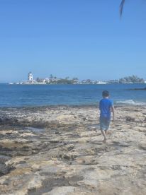 A child explores rocky shores with a picturesque lighthouse in the background, capturing the essence of a fun-filled day at the beach.