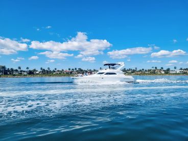 A sleek yacht cruising through calm waters under a bright blue sky, showcasing the perfect day for boating adventures.