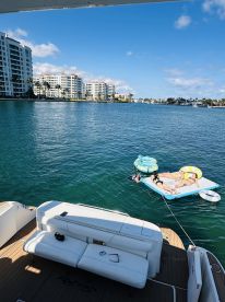 A group enjoys a sunny day on the water, relaxing on a floating mat while soaking up the sun — a perfect day for fun and relaxation.