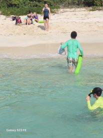 A lively group enjoys a beach day, with some swimming and snorkeling in the clear waters, creating memorable moments under the sun.