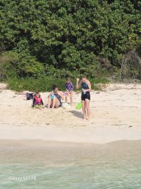 A joyful group of children and adults enjoying a sunny day at the beach, making memories and having fun in the sand.