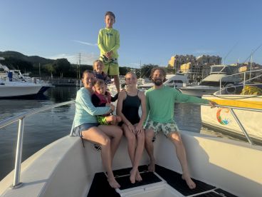 A joyful family poses together on a boat at the marina, capturing a moment of fun and togetherness before their aquatic adventure.