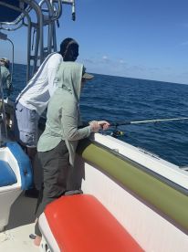 Two individuals enjoy a fishing experience on a boat, showcasing the excitement of on-water activities. Perfect for fishing enthusiasts looking for adventure.