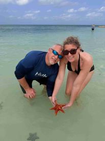 A couple interacts with a vibrant starfish in shallow waters, showcasing a memorable wildlife encounter during their aquatic adventure.