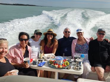 A joyful group enjoys a fun day on the water, sharing food and drinks while cruising on a boat — perfect for celebrations and gatherings.