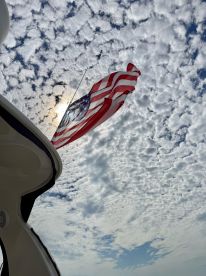 A striking view of a boat's flag against a backdrop of textured clouds, showcasing the vessel's identity and the beauty of a day on the water.