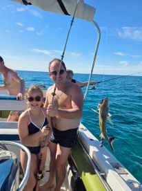 A joyful moment as a father and daughter celebrate their fishing catch aboard a boat, showcasing a fun family experience on the water.