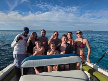 A cheerful group of friends and family enjoy cocktails on a boat, celebrating together under the sun — perfect for memorable outings on the water.