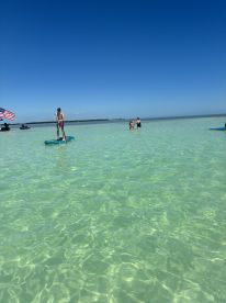 A fun day in clear waters with people paddleboarding and enjoying the sun — perfect for family outings and water sports adventures.