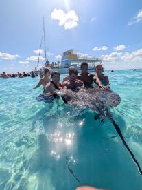 A group of people interacts with a stingray in crystal-clear waters, creating a memorable wildlife experience during their aquatic adventure.
