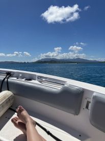 A relaxing view from the deck of a boat, showcasing a beautiful ocean scene with a distant island — perfect for enjoying sunny days on the water.