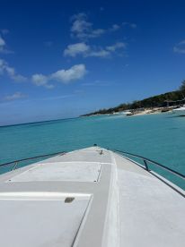 A stunning view from the front of a boat cruising through crystal-clear turquoise waters, showcasing the beauty of a tropical destination.