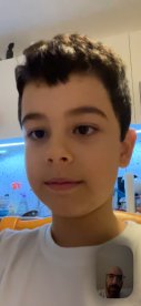 A close-up of a child in a room, with a visible social media handle in the corner.