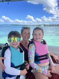 A joyful family moment on a boat, featuring a mother and her two children wearing life jackets, ready for a fun day on the water.