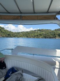 A cozy interior view of a boat's seating area, showcasing the serene waters and lush greenery outside — perfect for relaxing on a day out at sea.