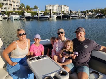 A cheerful family enjoys a sunny day on their boat, capturing a moment of joy and togetherness on the water.