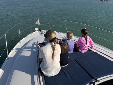 A group of children enjoys the view from the front of a boat, creating cherished family memories on the water.