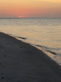 A serene sunset over the water, capturing the tranquil beauty of the shoreline. Ideal for those seeking peaceful beach moments.