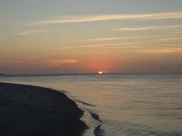 A stunning sunset over the tranquil waters, casting vibrant colors across the sky — a perfect backdrop for evening boat trips and beach relaxation.