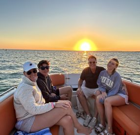 A joyful family enjoys a sunset cruise on a boat, capturing a perfect moment of togetherness against the backdrop of a stunning sunset.