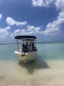 A group of friends enjoys a day on the water, gathered on a boat anchored near a beautiful beach — perfect for sun-soaked adventures and memorable outings.