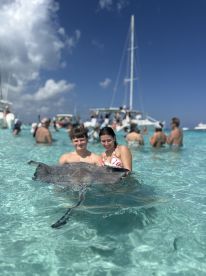 A memorable encounter as two young swimmers interact with a stingray in crystal-clear waters, showcasing the thrill of wildlife experiences in the Bahamas.