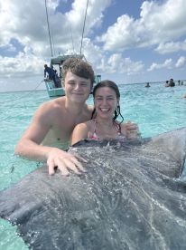 A joyful moment as two young swimmers interact with a stingray in crystal-clear waters, showcasing a unique wildlife experience in the Bahamas.