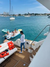 A lively group enjoys a fun day on the water, with some swimming and relaxing on a floating mat, showcasing the perfect atmosphere for family outings or friends' gatherings.