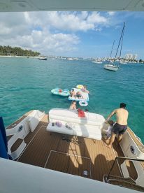 A family enjoys a fun day on the water, relaxing on inflatable floats while anchored near a beautiful beach — perfect for summer outings and family adventures.