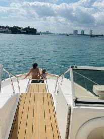 A mother and child enjoy a serene moment on the bow of a boat, surrounded by beautiful water views — perfect for family outings and relaxation on the water.