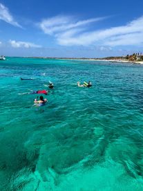 A group enjoys snorkeling in the crystal-clear turquoise waters, showcasing the vibrant marine life and perfect conditions for underwater exploration.