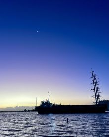 A silhouette of a ship against a stunning sunset sky, showcasing the tranquil beauty of the waterway at dusk.