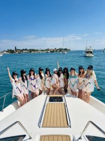 A lively group of friends celebrates aboard a yacht, showcasing fun outfits and a festive atmosphere — perfect for bachelorette parties or group outings on the water.