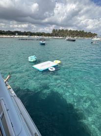 A vibrant floating mat and inflatable rings are anchored in clear waters, perfect for a day of fun and relaxation on the water.
