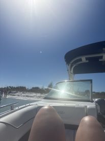 A relaxing moment on a boat with legs visible, enjoying the sunny beach backdrop — perfect for a day of fun and relaxation on the water.