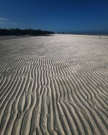 A scenic view of a sandy beach with unique patterns, showcasing the natural beauty of the shoreline.