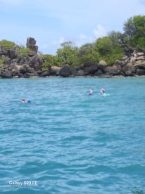 Two snorkelers explore the vibrant waters near a rocky island, showcasing the beauty of marine life and adventure in a tropical paradise.