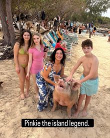 A group of friends interacts with Pinkie, the famous swimming pig, on the beach — a delightful wildlife encounter that showcases the charm of island adventures.