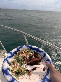 A delicious plate of salad and meat enjoyed on a boat, perfect for a relaxing meal while cruising on the water.