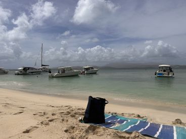 A picturesque beach scene featuring several boats anchored in calm waters, perfect for a relaxing day by the shore.